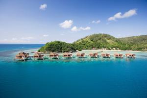 Tahiti Overwater bungalows in a tropical setting with clear blue waters.