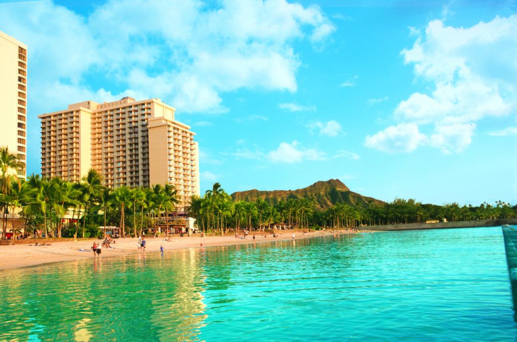 Tropical Waikiki Beachfront with a high-rise hotel and a distant mountain view.