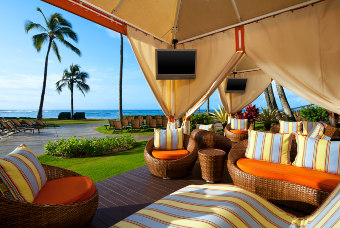 A patio with an umbrella and chairs on the ground