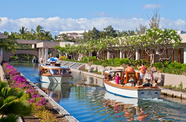 A boat navigates a serene canal, carrying passengers who enjoy the scenic views along the waterway.