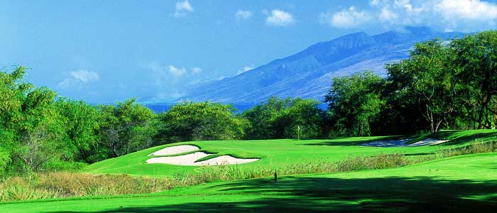 A Maui golf course with trees and mountains in the background.