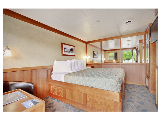 Elegant cabin bedroom on a private yacht in Hawaii with a large bed, wooden paneling, and maritime decor.
